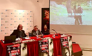 2. En la mesa, de izquierda a derecha, el director Juan Pinzás, el coordinador de Actos  Ramón Jiménez y la productora Pilar Sueiro con una imagen del trailes de la película EL VIENTRE DE EUROPA.jpg