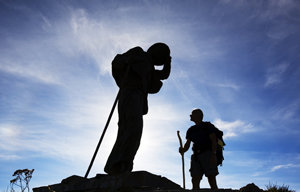 Un peregrino mirando a la escultura con la figura de bronce del alto de San Roque. O Poio. Camino de Santiago. Lugo. Galicia