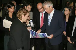 María José Porteiro, delegada de la Xunta en Argentina, muestra a Touriño un cartel sobre cambio climático.