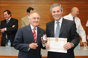  Emiliano Isla Verde hace entrega de Diploma y Medalla a Carlos Santos por sus 50 años de socio en el Hospital Español.