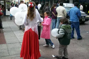  Una joven de la colectividad reparte globos a los niños que se acercaron a la sede de la entidad el pasado día 8.