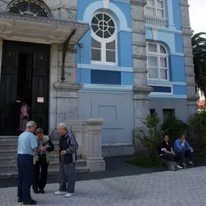 Varios emigrantes esperan a sus compañeros a la entrada del edificio. 