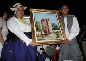 Dos jóvenes de la Agrupación Coros y Danzas de La Gomera, dan como ofrenda a la Virgen de Guadalupe una pintura de la célebre ‘Torre del Conde’ ubicada en la capital de la isla colombina.