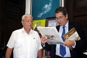  Manuel Cacho lee, junto a Carmelo González, el semanario ‘Galicia en el Mundo’.