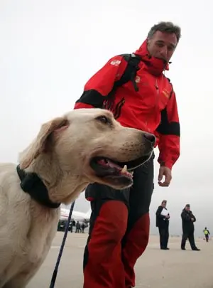 Un miembro del equipo de rescate junto a uno de los perros utilizados.