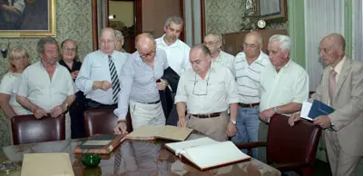 Camba observa el libro de actas fundacional del centenario Centro Gallego de Avellaneda. Le acompa&ntilde;an directivos de la casa.
