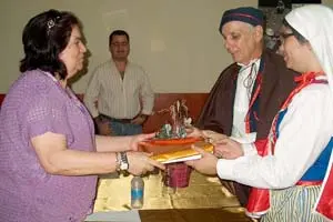  La viceconsejera canaria de Emigración recibe unos obsequios por parte del CCEC, de manos de dos socios ataviados con trajes típicos.