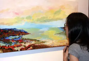 Una joven observa en la sala L una obra de la serie luces