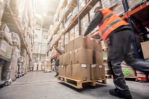 Motion blur of two men moving boxes in a warehouse.