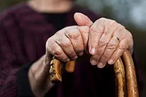 Close-up of senior woman's hands holding her walking sticks. Selective focus on hands and sticks.