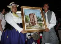  Dos jóvenes de la Agrupación Coros y Danzas de La Gomera, dan como ofrenda a la Virgen de Guadalupe una pintura de la célebre ‘Torre del Conde’ ubicada en la capital de la isla colombina. 