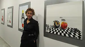 La pintora Conchi Cuadrado y algunos de los cuadros que componen la muestra