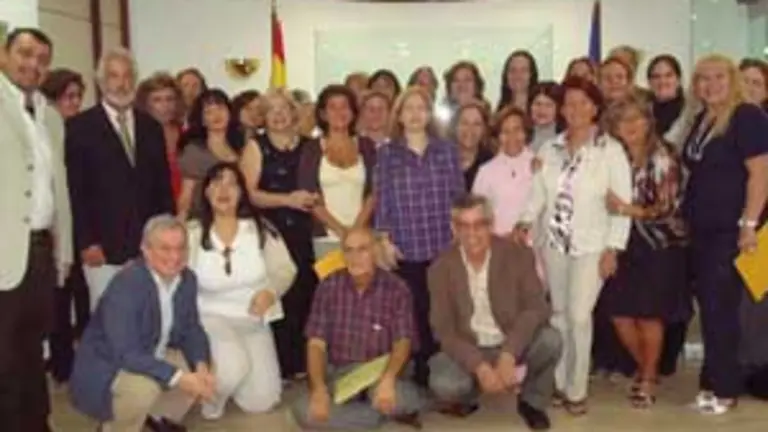 El consejero de Trabajo, el jefe de Gestión de la Consejería de Trabajo e Inmigración, Junta Directiva de la FEDED, así como representantes de las asociaciones, posan junto a las 22 nuevas cuidadoras.