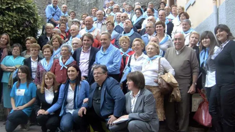 Las autoridades y el homenajeado posan con los emigrantes retornados participantes en el encuentro.