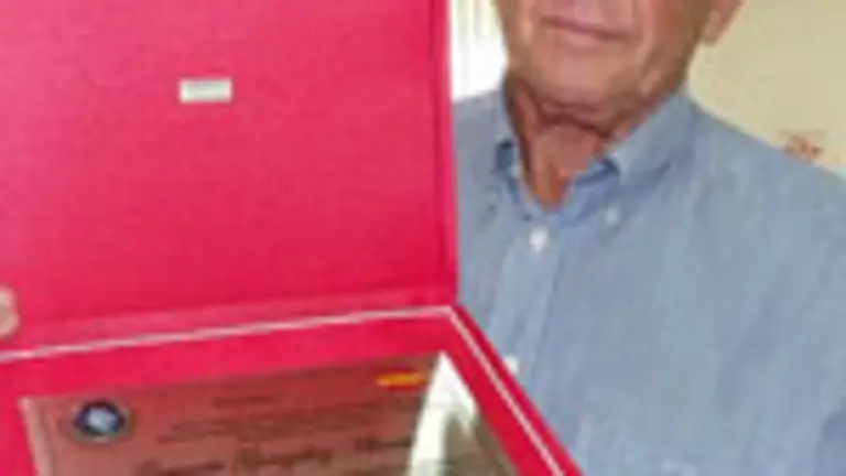  Gerardo Gonz&aacute;lez muestra la placa de homenaje por sus a&ntilde;os de dedicaci&oacute;n.    