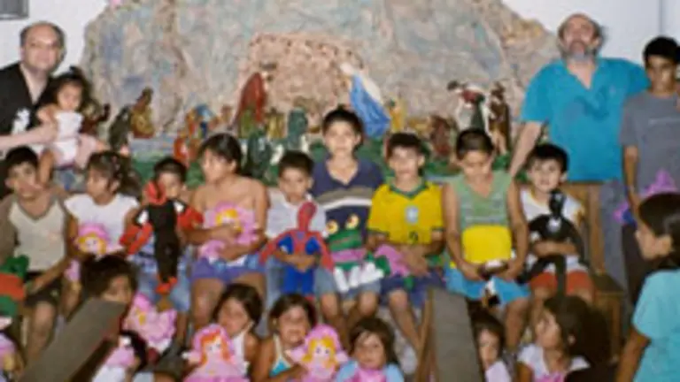  Rodríguez Velasco, ante el Nacimiento de Santa Eulalia, con el párroco y los niños a los que llevó regalos en Navidad.