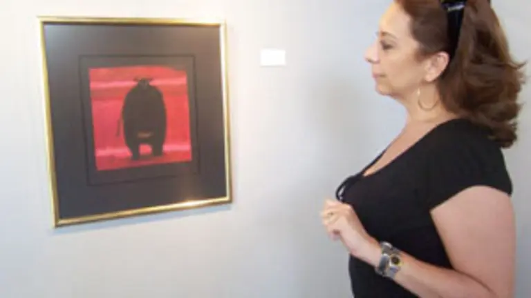 Una mujer contempla uno de los cuadros que componen la exposici&oacute;n.