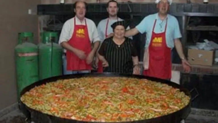 Los responsables de la paella muestran orgullosos su obra.