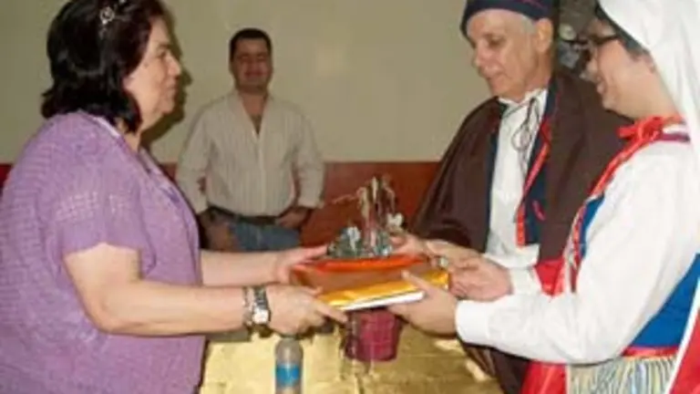  La viceconsejera canaria de Emigración recibe unos obsequios por parte del CCEC, de manos de dos socios ataviados con trajes típicos.