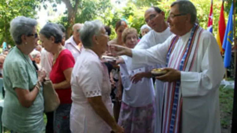  El sacerdote asturiano Alfonso Garc&iacute;a reparte la comunicaci&oacute;n entre los asistentes a la misa.