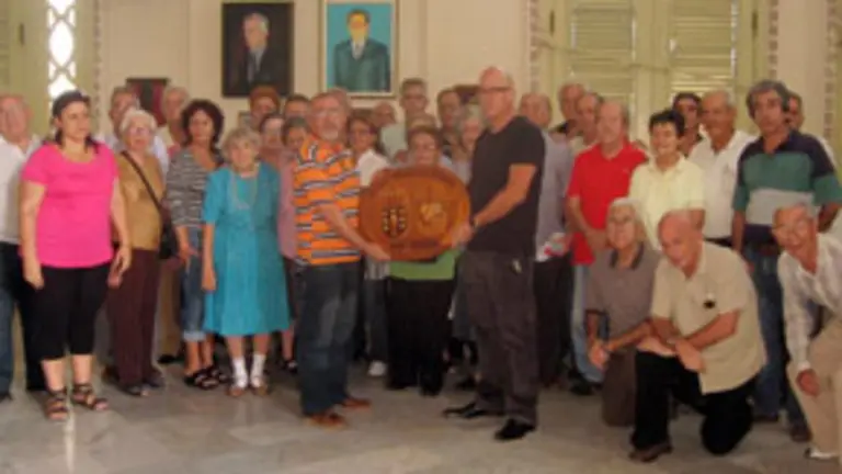 Los gallegos de Cuba enviaron un saludo a Fraga y mostraron la talla de madera con la que le van a obsequiar. 
