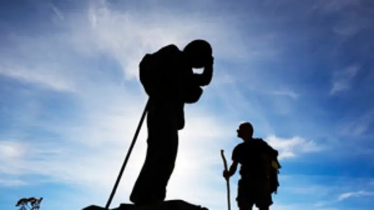 Un peregrino mirando a la escultura con la figura de bronce del alto de San Roque. O Poio. Camino de Santiago. Lugo. Galicia