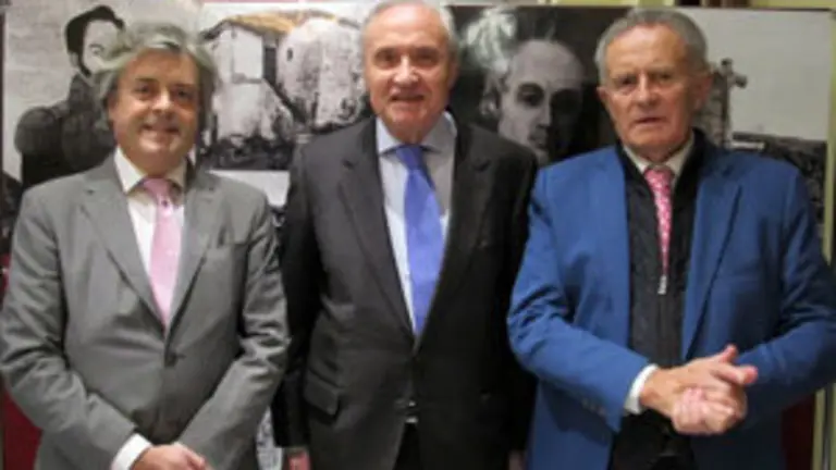 Esteban Meruéndano, el delegado de la Xunta, José Ramón Ónega, y Rodríguez Iglesias posan ante un panel con imágenes del libro