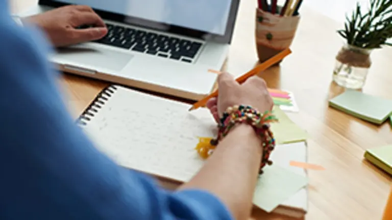 Female student working on project at home, view over the shoulder, selective focus