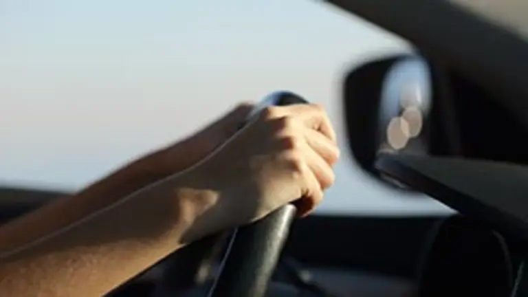 Driver hands holding steering wheel driving a car