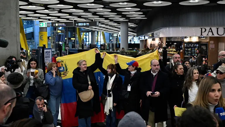 MADRID, 09/01/2026.- Un grupo de personas sostiene una bandera de Venezuela en el Aeropuerto Adolfo Su&middot;rez Madrid Barajas, este viernes. Los cinco presos espa&Ograve;oles liberados en Venezuela llegaron a Madrid este viernes en un vuelo procedente de Bogot&middot;, seg˙n confirm&Ucirc; el ministro de Asuntos Exteriores, Jos&Egrave; Manuel Albares, en un mensaje en la red social X. EFE/Fernando Villar
