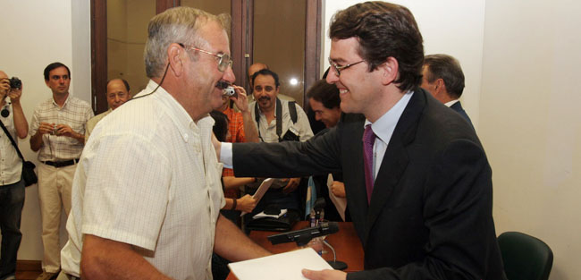 Mañueco entrega la documentación a otro de los beneficiarios.