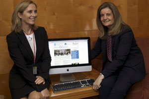 Fátima Báñez –derecha– y Marina Del Corral, junto a la pantalla de Crónicas de la Emigración, en el Pleno de 2014.