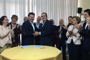 Los firmantes del acuerdo se saludan tras la rúbrica y son aplaudidos por los asistentes.