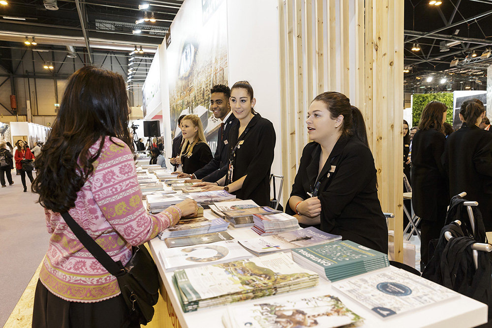 Alumnos de la Escuela de Turismo Altamira atienden el estand de Cantabria en Fitur.