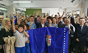 Baltar, acompañado por alumnos y directivos del colegio, posan en el patio cubierto del instituto.