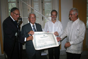 Carmelo González muestra el diploma de la concesión de la Medalla, junto a Cándido Padrón, el embajador, Juan Francisco Montalbán, y Miras Portugal.